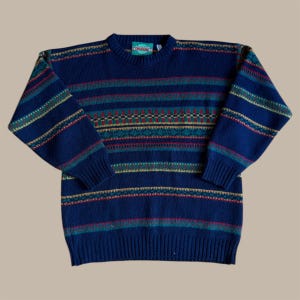 Könnte beinhalten: Ein marineblauer Pullover mit horizontalen Streifen in Türkis, Rot, Gelb und Grün. Der Pullover hat einen Rundhalsausschnitt und lange Ärmel. Das Etikett am Kragen lautet "L.L.Bean".
