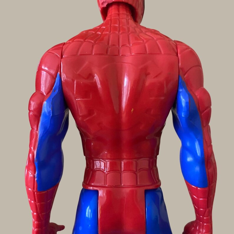 Puede incluir: Figura de acci&oacute;n de Spider-Man roja y azul, vista desde atr&aacute;s. La figura tiene un torso y cabeza rojos con un patr&oacute;n texturizado, y brazos y piernas azules. Es un juguete.