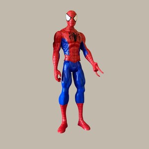 Puede incluir: Figura de acci&oacute;n de Spider-Man en una pose cl&aacute;sica. La figura es predominantemente roja y azul, con un emblema de ara&ntilde;a negra en el pecho. Los ojos son blancos y la figura tiene una apariencia texturizada y musculosa.