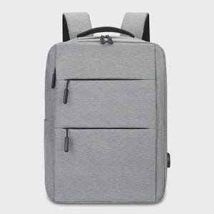 May include: A gray backpack with a rectangular shape. The backpack has two padded shoulder straps, a top handle, and multiple zippered compartments. It features a USB charging port on the side. The bag is made of a textured fabric.
