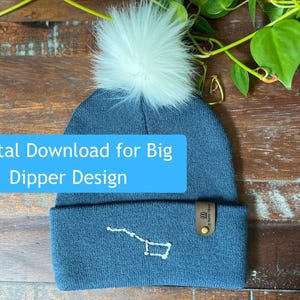 Può includere: Un berretto blu lavorato a maglia con un pompon bianco e un ricamo del design della costellazione dell'Orsa Maggiore. Il cappello ha un'etichetta in pelle marrone e il testo "Digital Download for Big Dipper Design" su un'etichetta blu.