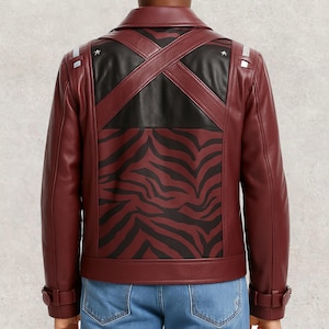 Puede incluir: Chaqueta de cuero burdeos con un panel de estampado de cebra negro en la espalda. La chaqueta tiene un diseño de correas cruzadas, detalles negros y detalles plateados en los hombros. Estilo motero clásico.