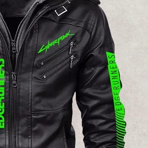 May include: Black faux leather jacket with a gray hooded insert. The jacket features the neon green text "Cyberpunk" and "EDGERUNNERS". The sleeves have green stripes and the text "EDGERUNNERS".