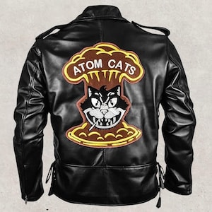 May include: Black leather jacket with a large embroidered patch on the back. The patch features a cartoon cat smoking a cigarette, with the words "ATOM CATS" above it, set against a mushroom cloud design.