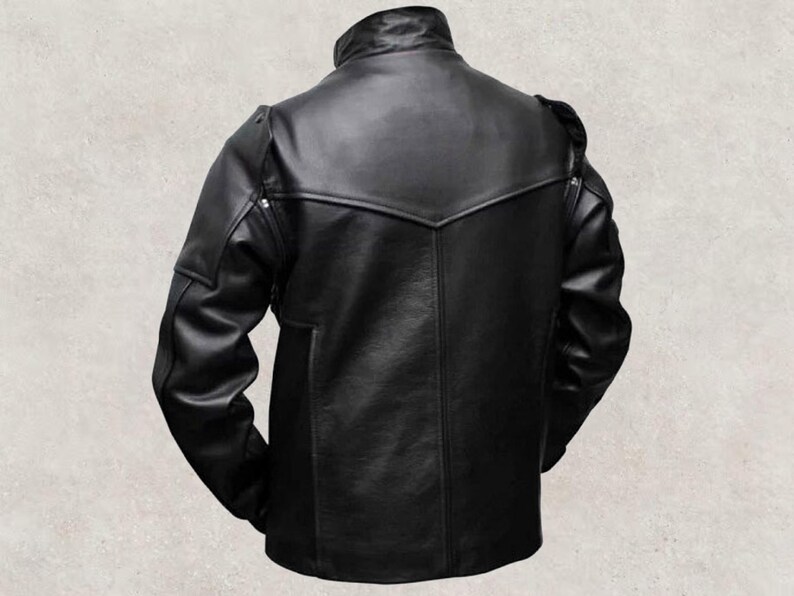 May include: A black leather jacket with a stand-up collar and a distinctive yoke design across the shoulders. The jacket has a tailored fit, long sleeves, and a subtle pocket detail on the lower front. The back view highlights the jacket's sleek, minimalist aesthetic.