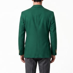 May include: A solid emerald green blazer with gold buttons. The tailored jacket has a classic two-button closure and notched lapels. The person in the image is wearing gray pants. The blazer is a versatile piece for formal or business attire.
