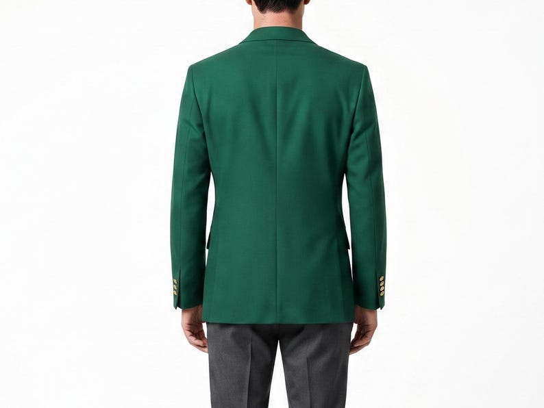May include: A solid emerald green blazer with gold buttons. The tailored jacket has a classic two-button closure and notched lapels. The person in the image is wearing gray pants. The blazer is a versatile piece for formal or business attire.