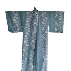 May include: A light blue kimono with a floral pattern. The kimono features vertical stripes and is adorned with white and pink floral designs. The sleeves are wide and the garment is open in the front.