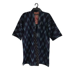 May include: A dark blue kimono-style jacket with a geometric pattern in light blue and white. The jacket has short sleeves and a contrasting red and pink floral lining. It hangs on a black hanger against a white background.