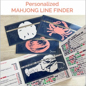 May include: Navy blue Mahjong line finders with personalized names. The cards feature illustrations of a sand dollar, crab, and lobster. The text "Personalized Mahjong Line Finder" is at the top.