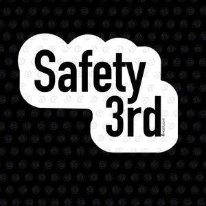 Puede incluir: Una pegatina blanca con las palabras "Safety 3rd" en letras negras en negrita. El texto está dispuesto en forma de nube, con la palabra "Safety" encima de "3rd". El fondo es negro con un patrón repetitivo.
