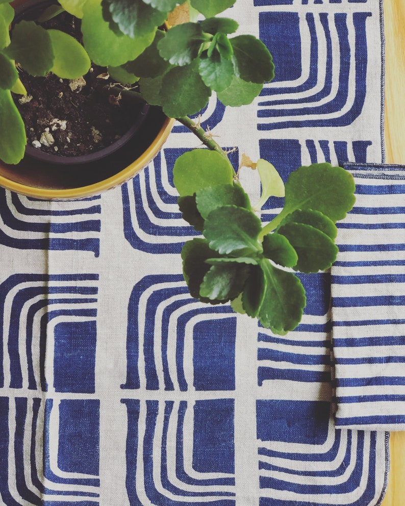 Blue retro design printed on natural linen paired with a blue striped napkin, decorative plant in corner of photo