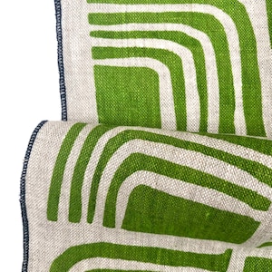 Op de afbeelding: Groen en wit geometrisch patroon stof met een marineblauwe rand. De stof heeft een linnen textuur.