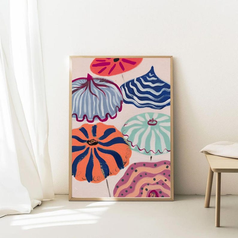 May include: A framed art print featuring a colorful abstract design of stylized umbrellas. The umbrellas are in various colors, including orange, blue, and teal, with striped and patterned details. The background is a soft pink, and the frame is a light wood color.