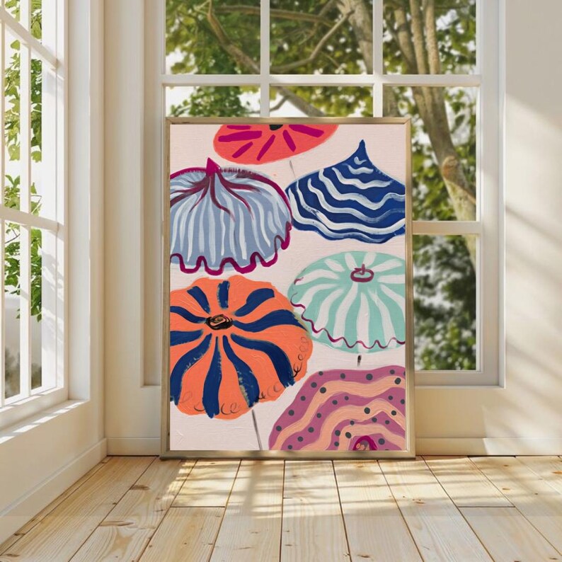 May include: A framed abstract art print featuring colorful umbrella-like shapes in shades of orange, blue, pink, and teal. The artwork has a light pink background and is displayed in a room with natural light.