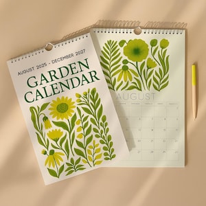 May include: Two open spiral-bound Garden Calendars, one showing the text "August 2025 - December 2027" and "Garden Calendar." The other calendar displays the month of August with floral illustrations in yellow and green. A yellow pencil is also visible.