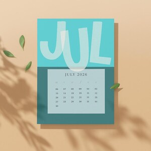 May include: A teal and turquoise July 2026 calendar with the month's name in large, white, stylized letters. The calendar grid is in a lighter teal, with dates visible. Green leaves are scattered around the calendar.