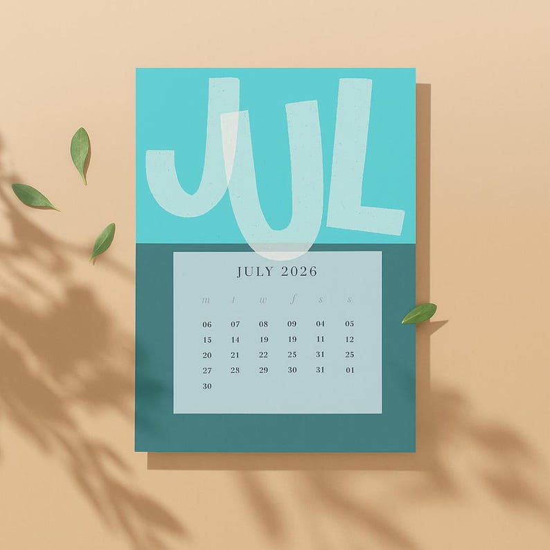 May include: A teal and turquoise July 2026 calendar with the month's name in large, white, stylized letters. The calendar grid is in a lighter teal, with dates visible. Green leaves are scattered around the calendar.