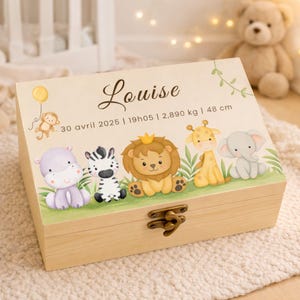 Peut inclure: Un coffret en bois avec un couvercle beige clair orné du nom "Louise" en écriture cursive. Le couvercle est décoré d'animaux de dessins animés : hippopotame, zèbre, lion, girafe et éléphant. Le coffret a un fermoir en métal. Le texte "30 avril 2025 | 19h05 | 2,890 kg | 48 cm".