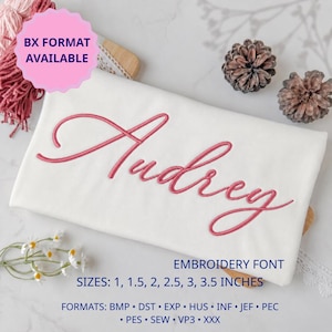 Puede incluir: Una muestra de tela blanca con el nombre Audrey bordado en letra cursiva rosa. El texto incluye BX FORMAT AVAILABLE, EMBROIDERY FONT, SIZES: 1, 1.5, 2, 2.5, 3, 3.5 INCHES y FORMATS: BMP, DST, EXP, HUS, INF, JEF, PEC, PES, SEW, VP3, XXX.