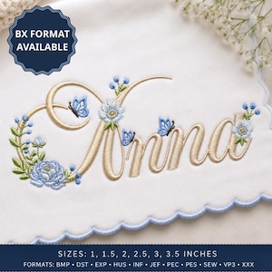 May include: An embroidery design on white fabric featuring the name Anna in gold script lettering, decorated with blue flowers, green leaves, and small blue butterflies. A dark blue badge states BX FORMAT AVAILABLE, and text lists sizes 2.54, 3.81, 5.08, 6.35, 7.62, 8.89 cm.