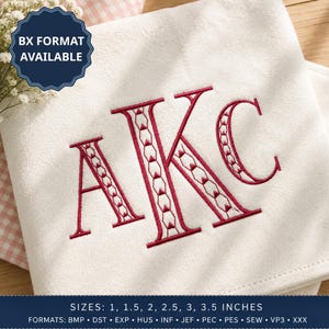 May include: A white fabric square featuring a large, embroidered monogram of the letters AKC in dark red thread. The letters have a decorative geometric pattern inside. A dark blue badge in the corner reads BX FORMAT AVAILABLE.