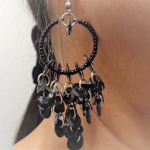 May include: Black hoop earrings with dangling black beads and silver accents.