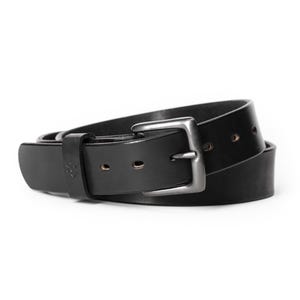 Op de afbeelding: Een zwarte leren riem met een zilverkleurige gesp. De riem is gemaakt van dik, duurzaam leer en heeft een klassiek ontwerp. De riem is ongeveer 3,8 cm breed.