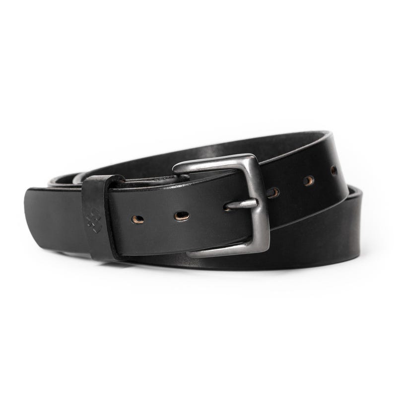 Op de afbeelding: Een zwarte leren riem met een zilverkleurige gesp. De riem is gemaakt van dik, duurzaam leer en heeft een klassiek ontwerp. De riem is ongeveer 3,8 cm breed.