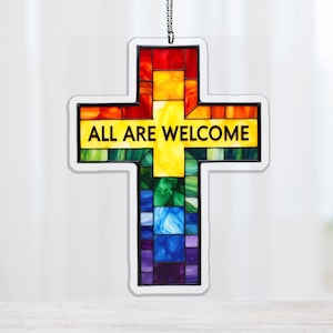 May include: A colorful cross-shaped ornament with a stained-glass effect. The cross features a rainbow of colors, including red, orange, yellow, green, blue, and purple. The text "ALL ARE WELCOME" is displayed in a bold, black font across the center.