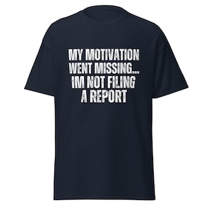 May include: Navy blue t-shirt with white text that reads "MY MOTIVATION WENT MISSING... IM NOT FILING A REPORT". The shirt has short sleeves and a crew neck.