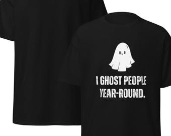 Peut inclure: T-shirt noir avec un motif de fantôme blanc et le texte "I GHOST PEOPLE YEAR-ROUND." Le design comprend une illustration de fantôme mignon. C'est un vêtement décontracté.