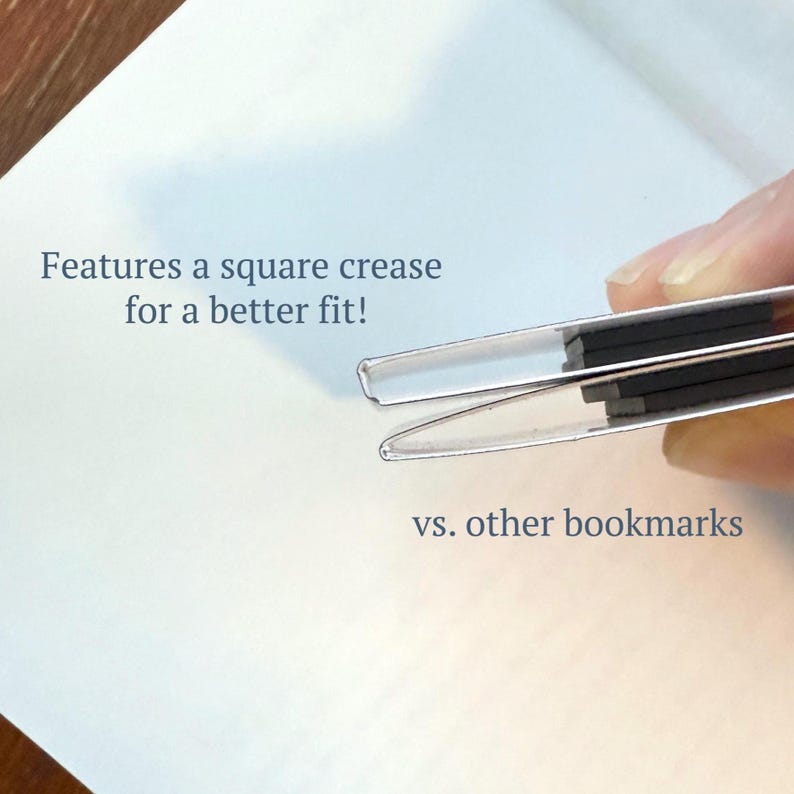 May include: Close-up of a silver bookmark with a square crease, held against a white background. The text reads, "Features a square crease for a better fit!" and "vs. other bookmarks."