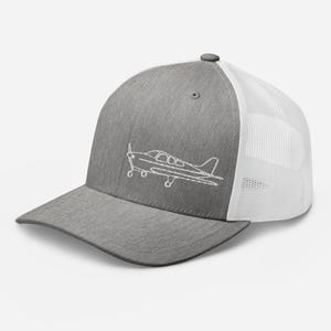 Könnte beinhalten: Graue Trucker-Cap mit weißem Mesh-Rücken und gebogenem Schirm. Auf der Vorderseite ist eine weiße, gestickte Umrisszeichnung eines kleinen Flugzeugs zu sehen. Mit verstellbarem Druckknopfverschluss.