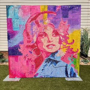 May include: A large square wall display composed of numerous small, reflective, shimmering square tiles. The tiles are arranged to form a vibrant, multi-colored portrait of a person with voluminous hair, rendered in shades of pink, purple, blue, and yellow.