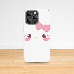 May include: A white phone case featuring a cartoon face with a pink bow, pink cheeks, and a yellow nose. The phone case has a triple-lens camera.