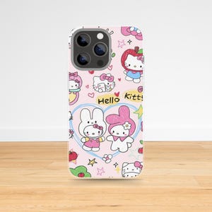 May include: Pink phone case featuring a repeating pattern of Hello Kitty and My Melody characters, apples, hearts, and stars. The words "Hello Kitty!" are also visible. The case has a silver camera lens.