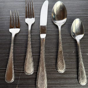 Może przedstawiać: Zestaw trzech ceramicznych wazonów o różnych wysokościach. Wazony są białe z matowym wykończeniem i mają teksturowany, żebrowany wzór. Najwyższy wazon ma około 25 cm wysokości.