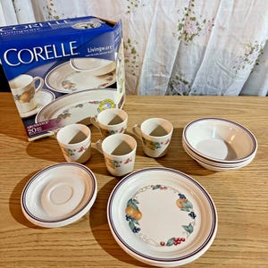 Puede incluir: Juego de vajilla Corelle Livingware de 20 piezas con diseño de frutas. Incluye platos, cuencos, platillos y tazas. La vajilla blanca tiene un borde azul y un patrón de frutas de naranjas, bayas y hojas.