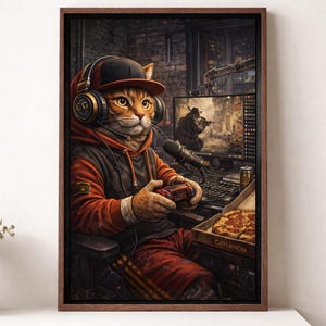 Könnte beinhalten: Gerahmter Kunstdruck eines spielenden Katzens, der ein Headset und eine Kappe trägt und ein Videospiel spielt. Die Katze trägt einen rot-schwarzen Kapuzenpullover und eine Hose und hält einen Controller. Eine Pizzaschachtel steht daneben.