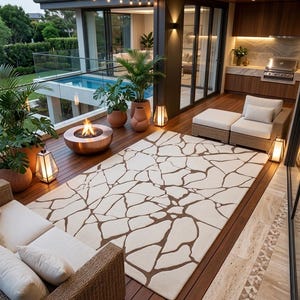 May include: A rectangular area rug featuring a cream-coloured background with a dark brown, irregular stone-like mosaic pattern. The rug is positioned on a wooden deck, surrounded by outdoor furniture, potted plants, and a circular fire pit.