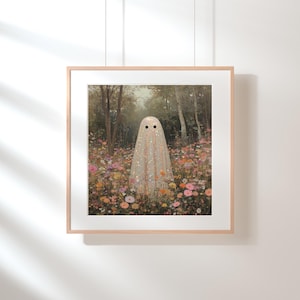 May include: A framed art print featuring a whimsical ghost figure in a field of colorful flowers. The ghost is draped in a shimmering, glittery fabric with two black dot eyes. The background shows a forest with trees and a soft, natural light.