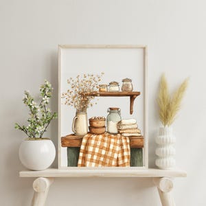 May include: Watercolor print of a rustic kitchen scene. A wooden shelf displays jars, bowls, and a checkered cloth. Dried flowers and decorative vases flank the framed artwork, creating a cozy, farmhouse aesthetic.