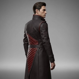 May include: A long, dark brown coat with red accents. The coat features a high collar, quilted shoulders, and a diagonal red panel on the front. It has a belt at the waist and buttoned cuffs. The coat appears to be made of leather or a similar material.