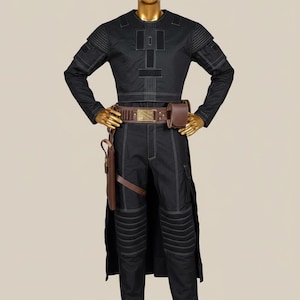May include: Black costume with white stitching, displayed on a mannequin. The outfit includes a long-sleeved top, pants, and a brown belt with a pouch. A holster is attached to the belt. The mannequin has a gold head and hands.