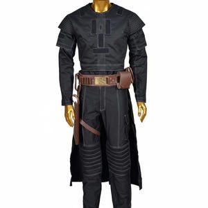 May include: Black costume with white stitching, featuring a long-sleeved top, pants, and a belt with a pouch. The costume includes a long, black cape and brown accessories. The mannequin has a gold head.