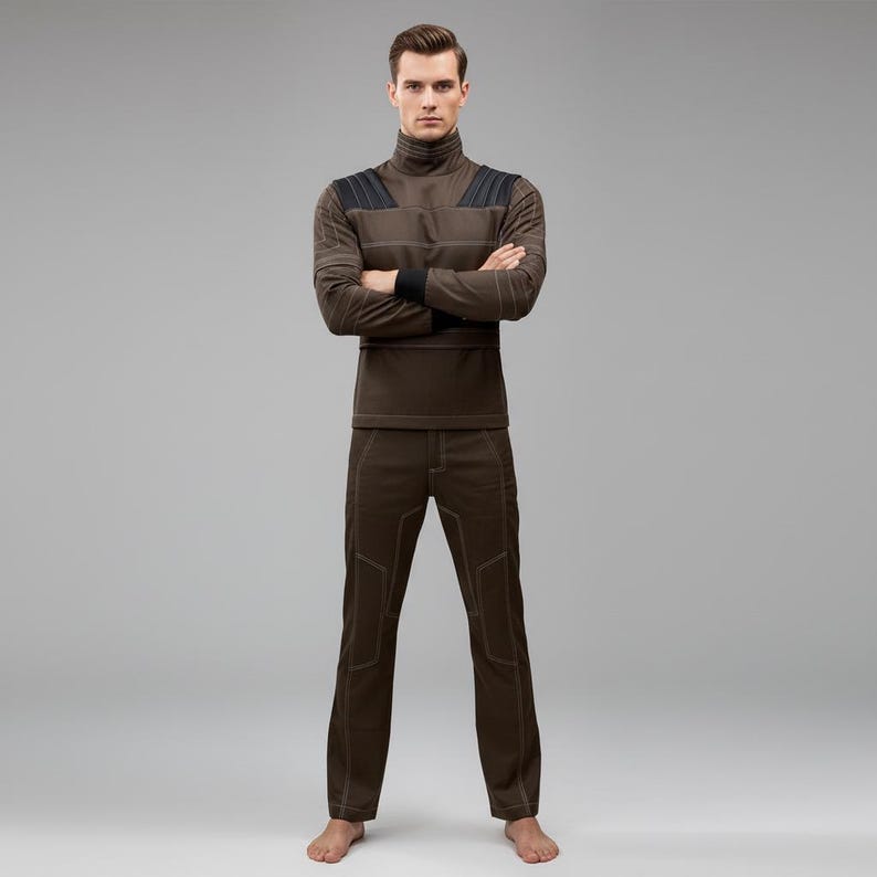 May include: A brown turtleneck long-sleeve shirt and matching pants. The shirt has black accents on the shoulders and cuffs, with visible stitching. The pants have a similar design with visible stitching. The outfit is a solid color and appears to be made of a comfortable material.