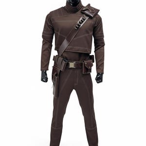 May include: A brown costume with white stitching, displayed on a mannequin. The outfit includes a long-sleeved top, pants, and a belt with pouches. A shoulder strap and additional pouches are also visible. The costume is designed with a high collar.