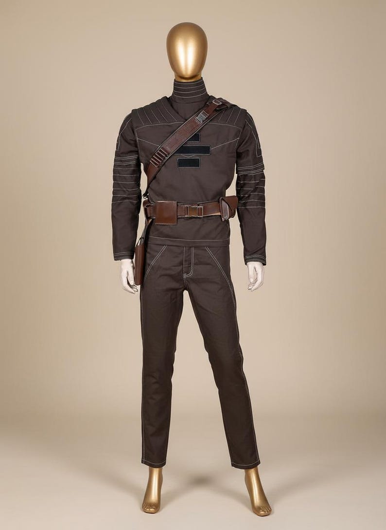 Puede incluir: Un disfraz marr&oacute;n exhibido en un maniqu&iacute;. El atuendo incluye un top de cuello alto, pantalones y un cintur&oacute;n con una funda. Las costuras blancas acent&uacute;an las costuras. Una correa de hombro marr&oacute;n y un cintur&oacute;n con una bolsa completan el look. El maniqu&iacute; tiene una cabeza dorada.