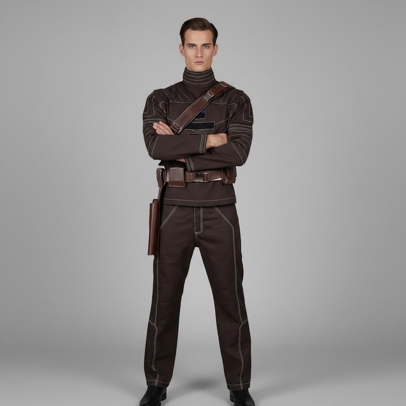 May include: A brown uniform with white stitching, a high collar, and a leather belt and holster. The outfit includes a long-sleeved top and matching pants. The person is wearing black shoes and has their arms crossed.